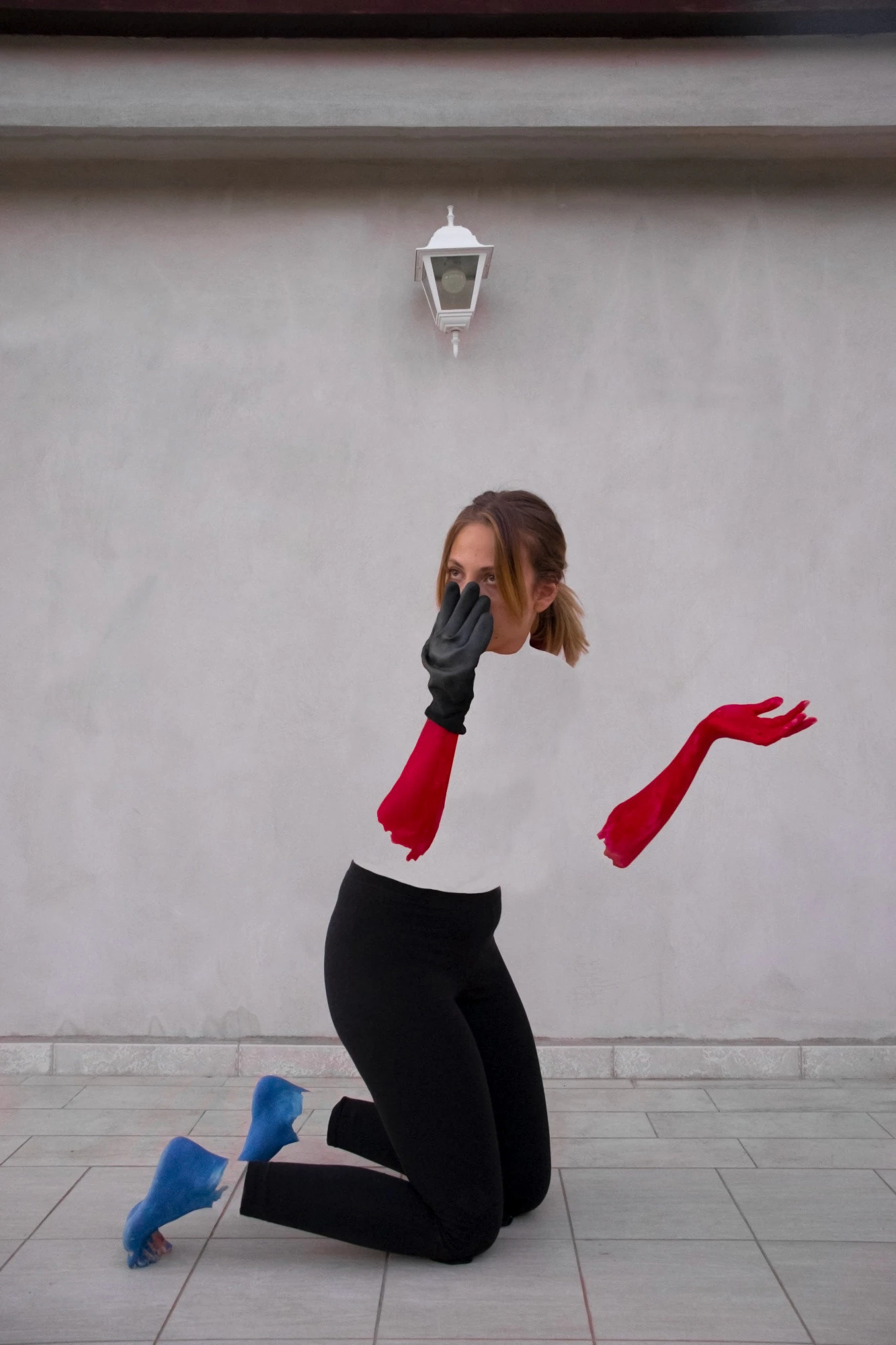 A portrait: a woman kneeling with red arms, under a wall lamp.