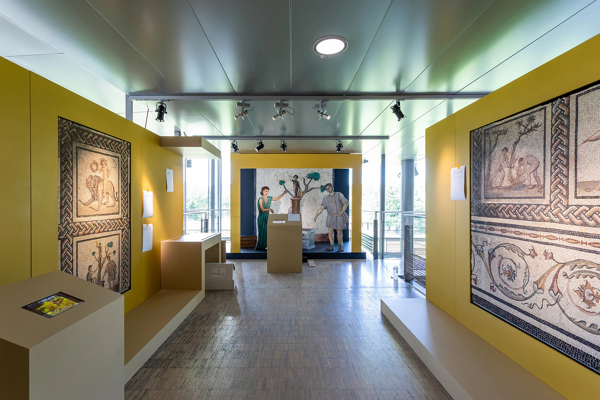 A yellow room of the exhibition, with mosaics and an interactive station.