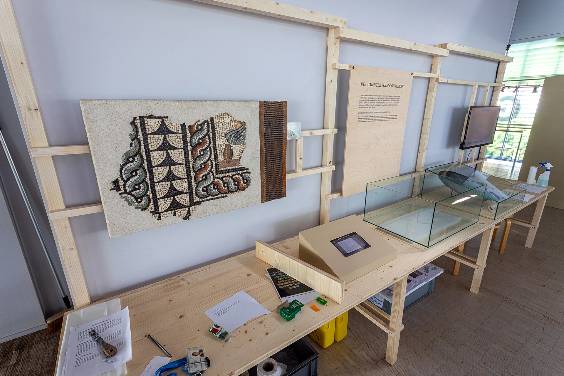 A restoration workbench with a piece of mosaic and a screen.