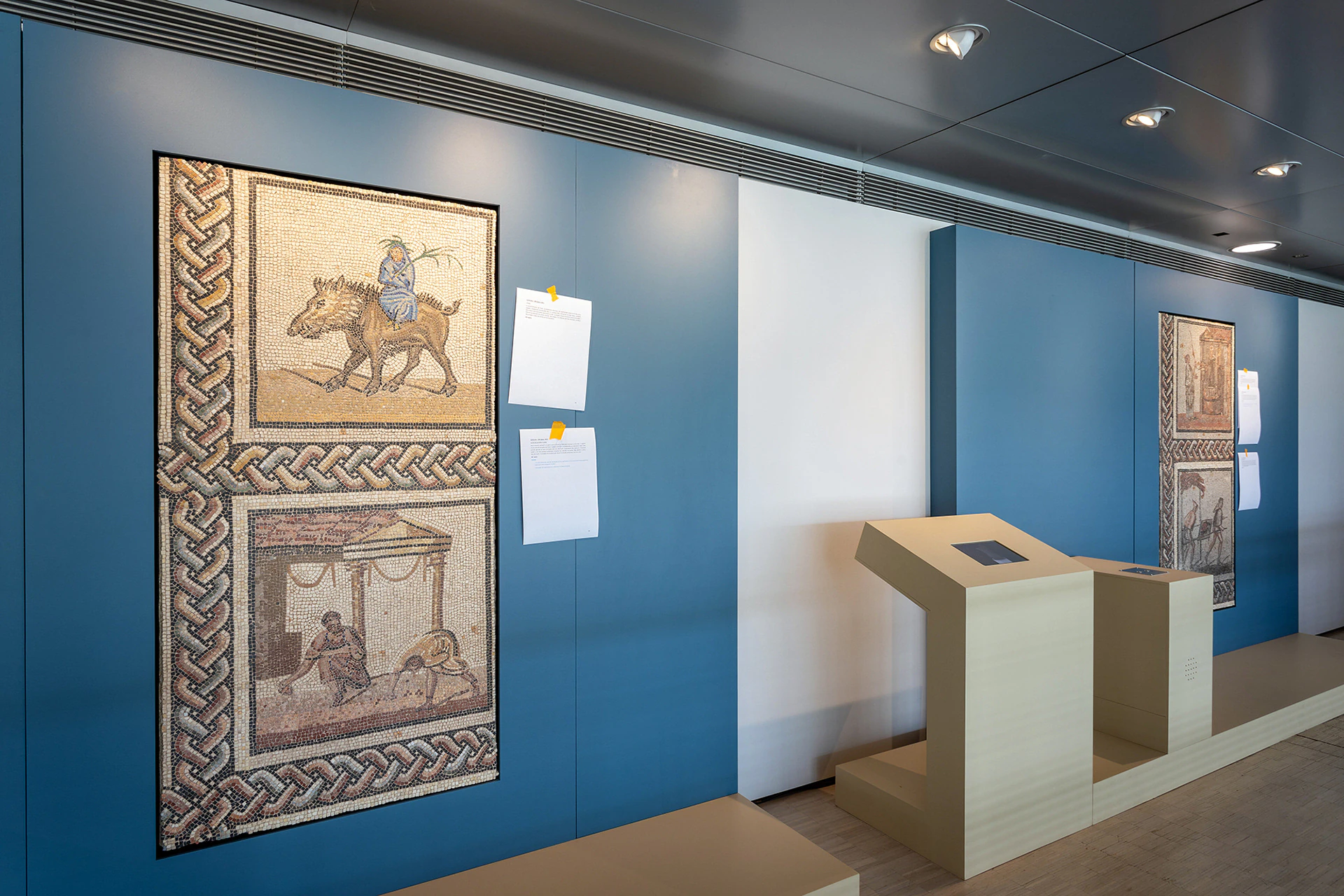 Mosaics on a blue wall, with a station in front of them.