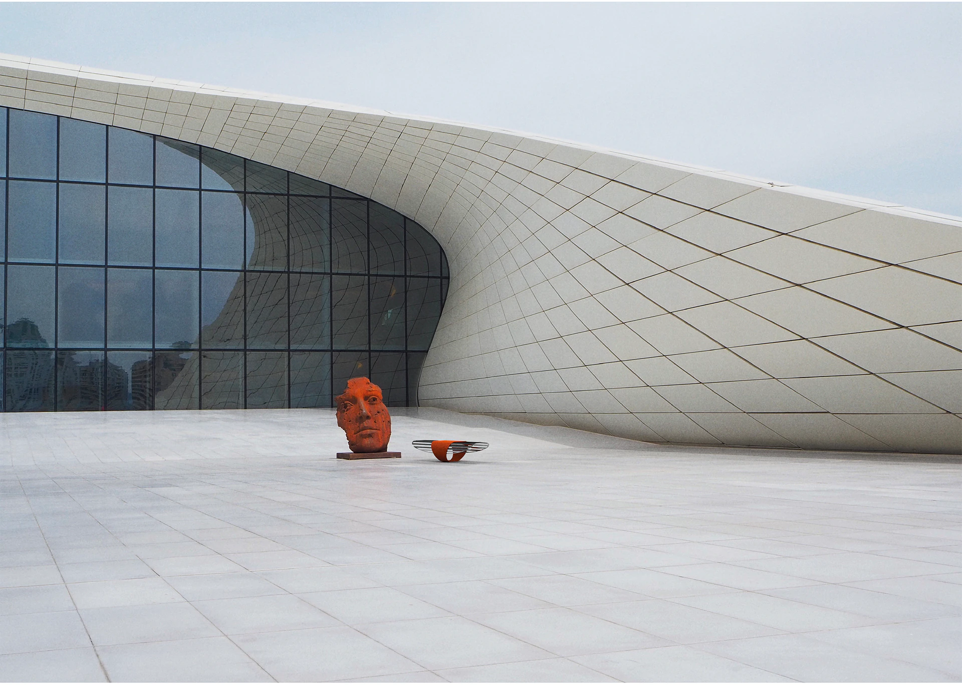 The Corten bench in front of a curved white building.