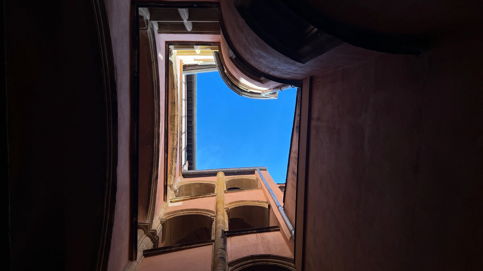 Looking up from the courtyard of a traboule to the sky.