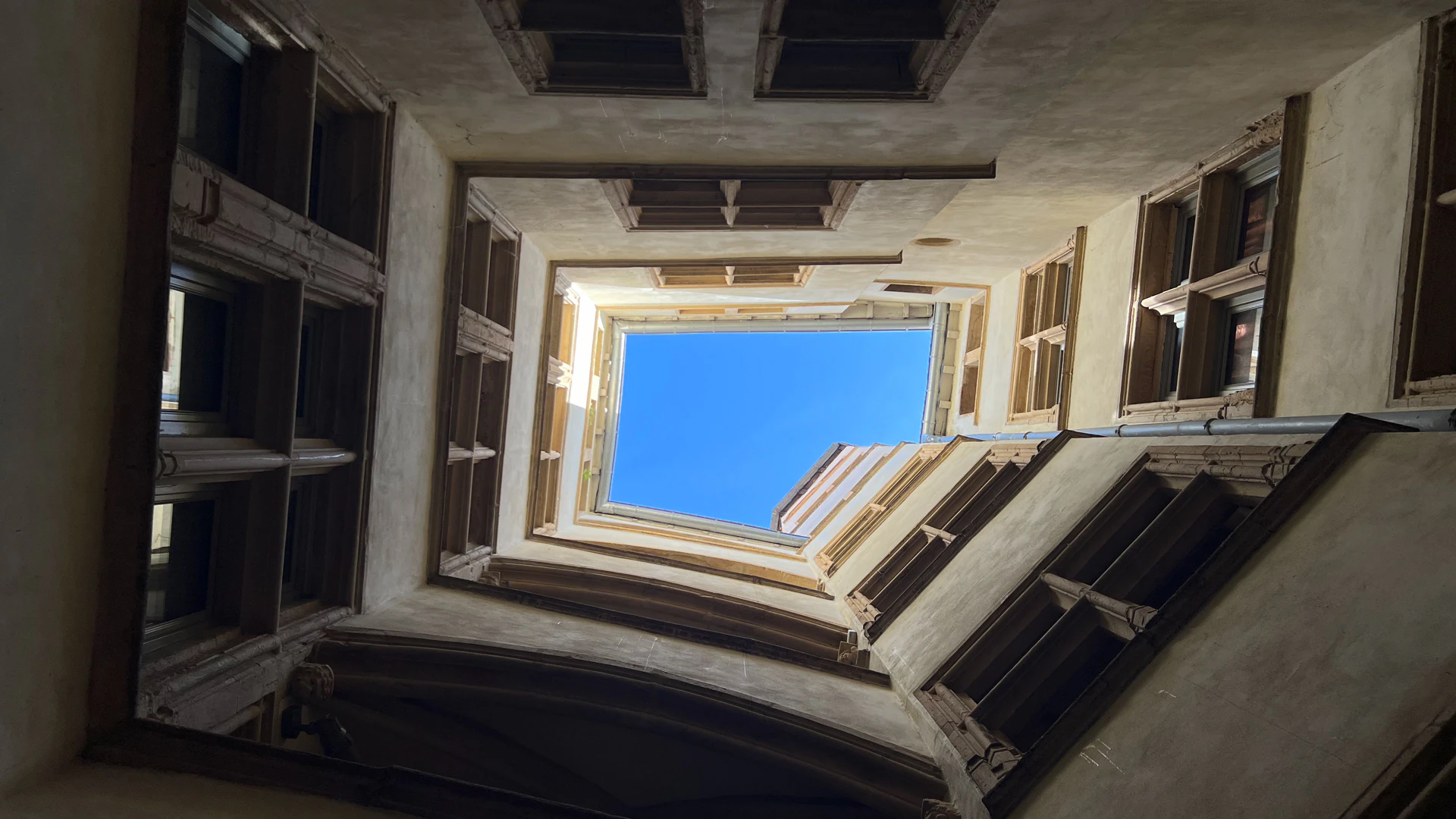Looking up from a traboule courtyard with galleries on four sides.