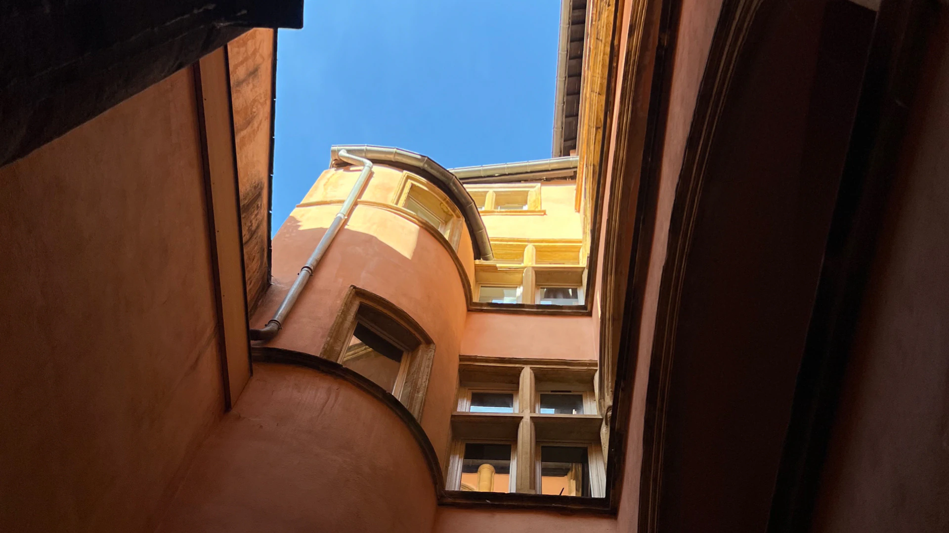 Looking up through a narrow traboule courtyard.